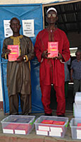 Herr A. Manneh (Bibliothekar) und Herr  A. Bojang (Elternvertreter) mit neuen Englisch-Wörterbüchern und Plastikboxen